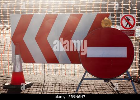 Umzäunung der Straße mit einem Maschendrahtzaun und Straßenschildern und -Kegeln für Reparaturarbeiten. Stockfoto