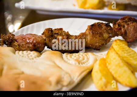 Teller mit gegrilltem Spieß, Kartoffeln und usbekischem Brot in einem Restaurant in Chiwa (Usbekistan) Stockfoto