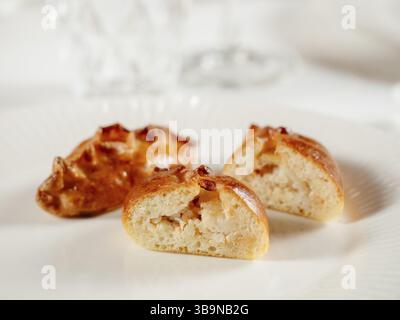 Kleine russische Torten mit gehacktem Lachsfisch russischer Piroschki. Gekochter Thunfisch handportionierte Torten oder Empanadas, halbiert auf weißer Platte in eleganter Form Stockfoto