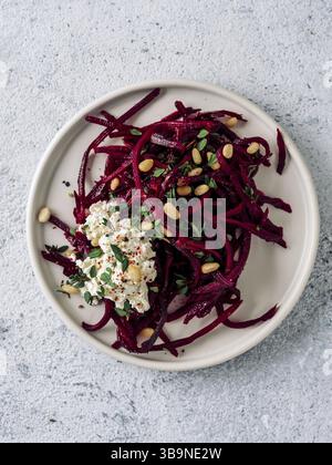 Roher Rote-Bete-Spaghetti-Salat mit Weichkäse, Nüssen, Thymian. Gemüsenudeln - frische Rote-Bete-Nudeln mit Ricotta und frischem Thymian auf Teller. Spac kopieren Stockfoto