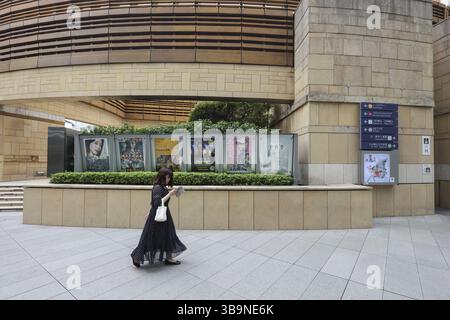 Frau, die ein Mobiltelefon benutzt, läuft an Filmplakaten im Einkaufs- und Bürokomplex Roppongi Hills, Tokio, Japan, Asien vorbei Stockfoto