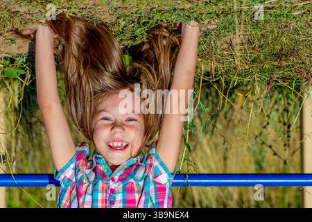Porträt eines lächelnden kaukasischen Kindes von 7 bis 8 Jahren mit Kopf über Fersen Stockfoto