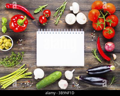 Notebook und Zutaten für das Kochen von Gemüse und Kräutern auf hölzernen Tisch Hintergrund. Ansicht von oben. Kopieren Sie Platz. Kochen Konzept. Mockup Stockfoto