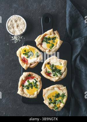 Ideen und Rezepte für gesunde vegane Shakshouka-Tassen mit veganen Tofu-Eiern und Kurkuma-Eigelb. Verzehrfertig. Blätterteig, Tomatensauce und grüne Par Stockfoto