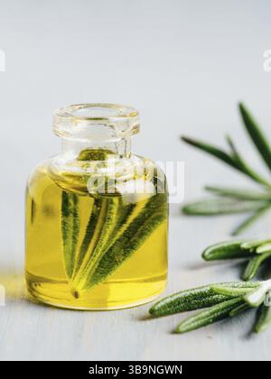 Rosmarin Öl. Rosemary wesentliches öl Öl in kleinen Fläschchen und Niederlassungen von frischem Rosmarin auf weißem Hintergrund. Kopieren Sie Platz für Text. Vertikale Stockfoto