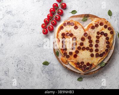 Vatertag Hintergrund mit Pizza in Herzform und Papa Wort. Pepperoni Pizza in Herzform mit Vati Schrift auf grauem Zement Hintergrund. Kopieren spac Stockfoto