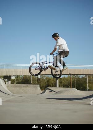 BMX Fahrradfahrer macht Stunt Bunny Hop Tailwhip. Ein erfahrener BMX-Freestyler springt und macht Flugtrick Tailwhip Flat oder Bunny Hop Tailwhip in Stockfoto