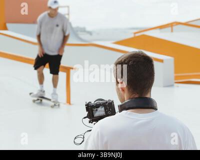 Videograf filmt Skateboarding im Skatepark. Professioneller Kameramann – Video über die Veranstaltung. Kameramann hinter der Szene. Filmaufnahmen des Ereignisses. Video Stockfoto
