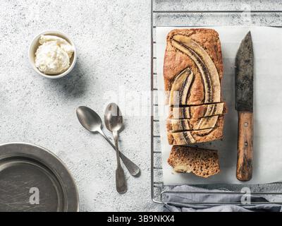 Butter, Zucker-freien Bananenbrot mit Hafermehl, weiche Quark und Honig. Blick von oben auf die bananenscheiben Brot auf grauzement Hintergrund. Ideen und Stockfoto