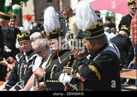 Sangerhausen, Deutschland. Mai 2025. Bergleute sitzen in ihren traditionellen Kostümen auf einer Bank und beobachten die Bergbauparade von 2025. Die Parade ist der Höhepunkt der Feierlichkeiten „825 Jahre Kupferschieferbergbau im Bergbaugebiet Sangerhausen“ und der Mansfelder Mulde. Der Bergbau hat die Landschaft und die Menschen in der Region geprägt und ist bis heute sichtbar. Quelle: Heiko Rebsch/dpa/Alamy Live News Stockfoto