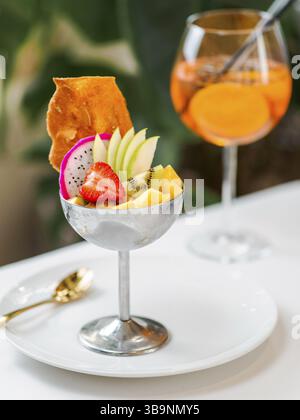 Tropical Paradise Sorbet mit Grapefruit, Mango, Passionsfrucht dekoriert mit frischem Obst und knusprigen Tuilkeksen. Tropisches Eis im Eisbecher aus Metall Stockfoto