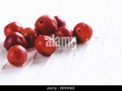 Haufen getrockneter rosafarbener Pfefferbeeren auf weißem Holztisch. Nahaufnahme des rosafarbenen Pfefferkörns. Kopierbereich Stockfoto