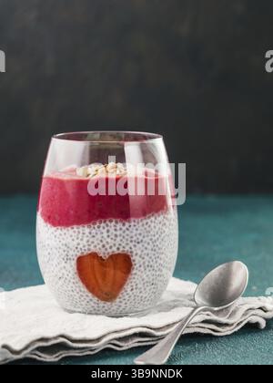 Idee für gesundes Frühstück am Valentinstag: Chia Pudding mit roten Beeren Püree, gehackte Mandeln auf und Erdbeere in der Form des Herzens. Kopieren Sie sp Stockfoto