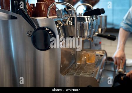 Professionelle Espressomaschine aus Edelstahl in einem Café mit Barista Tamping Kaffee Stockfoto