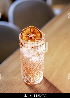 Transparenter rosafarbener Alkoholcocktail mit Eis, Wodka und Gin Tonic an der Bartheke im Restaurant. Alkohol Cocktail dekoriert Orangenscheibe. Kalt A Stockfoto