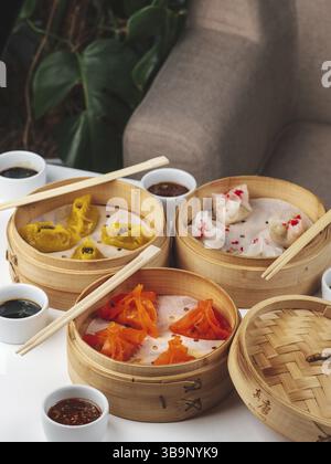 Dim Sum Geschirrset. Traditionelles Asan-Brunch. Gedämpfte Knödelgerichte mit Sojasauce auf dem Hintergrund des Restauranttisches. Dim Sum traditionelles Chinesisch und Stockfoto