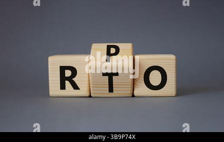 RPO vs. RTO-Symbol. Holzwürfel mit den Worten RTO zu RPO gedreht. Schöner grauer Hintergrund. Geschäftskonzept. Kopierbereich Stockfoto
