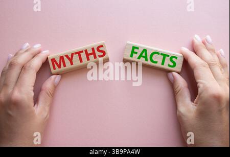 Symbol für Fakten oder Mythen. Konzeptwort Fakten oder Mythen auf Holzblöcken. Geschäftsmann Hand. Schöner rosafarbener Hintergrund. Business and Facts or Myths Concept. Stockfoto