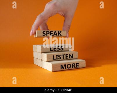 Weniger sagen, mehr hören. Holzblöcke mit Wörtern sprechen weniger Hören Sie mehr. Wunderschöner orangefarbener Hintergrund. Geschäftsmann Hand. Geschäftlich und weniger sprechen Stockfoto