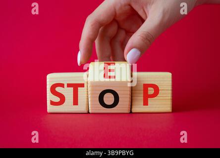 Symbol „Schritt vs. Stopp“. Die Hand des Geschäftsmannes dreht Holzwürfel und ändert das Wort Stop to Step. Schöner roter Hintergrund. Schritt vs. Stopp und Business Conceep Stockfoto