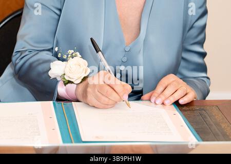 Eine Braut unterschreibt die Registrierungsunterlagen für die Ehe Stockfoto
