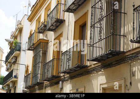 Traditionelle Fassade des Apartmentgebäudes mit schmiedeeisernen Balkonen und Fensterläden in Sevilla, Spanien, bei hellem Tageslicht fotografiert. Sevilla Stockfoto