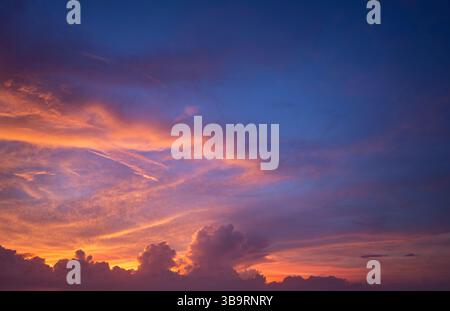 Heller Sonnenuntergang mit untergehender Sonne hinter leuchtenden orange und gelben Wolken Stockfoto