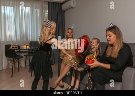 Geburtstagsparty Kinder Frauen Heimfeier: Familientreffen im Haus, feiern den Geburtstag eines Kindes mit Geschenken und Ballons. Stockfoto