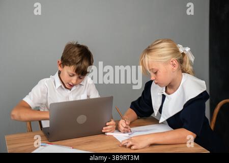 Laptop für Kinder – Junge und Mädchen machen Hausaufgaben an einem Schreibtisch mit Laptop. Stockfoto