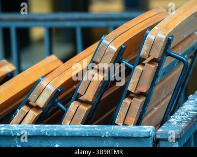 Aus nächster Nähe stapelbare Klappstühle aus Holz mit Metallrahmen, die ihr Design und ihre Textur zeigen. Die Stühle sind ordentlich angeordnet, was hervorhebt Stockfoto