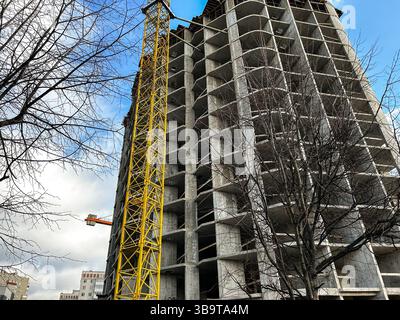 Mehrstöckiger Wohnkomplex im Bau mit gelbem Kran. Betonabschnitte. Bild für Wohnraumplanung und Immobilieninhalte Stockfoto