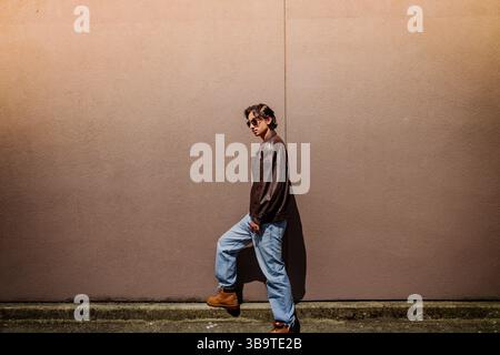 Mann im urbanen Stil posiert vor einer Mauer Stockfoto