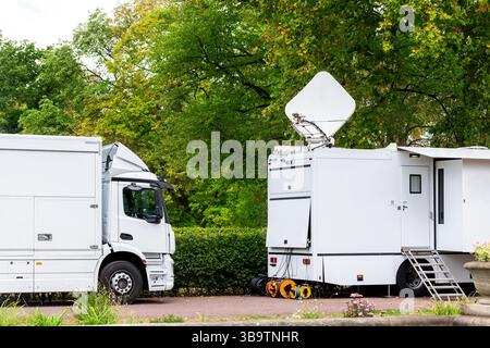 Viele moderne, weiße, mobile, digitale, elektrische tv-Übertragungswagen Satelliten-Antenne Live-Streaming Online-Nachrichten Sportsender Stadtpark Stockfoto