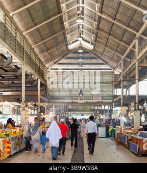 Bandar Seri Begawan, Brunei - 6. Februar 2025: Blick von innen auf den belebten Nachtmarkt von Gadong, mit Menschen, die unter einem hohen Industriedach an Imbissständen und Einzelhandelsständen vorbeilaufen Stockfoto