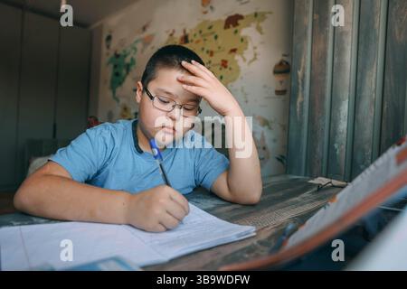 asiatischer Junge mit einer Brille, die frustriert den Kopf hält, Schulaufgabe am Schreibtisch in der Nähe der Welt, Landkarte, Konzept der Hausschulung, Bildungsdienst Stockfoto