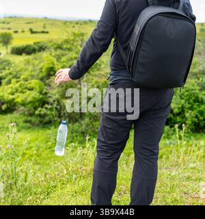 Verantwortungsloser Wanderer, der eine Plastikflasche auf den Boden wirft und die Natur verschmutzt Stockfoto