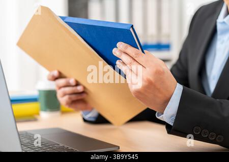 Nahaufnahme eines leitenden Mannes, der Paketzustellung mit Terminkalender im Büro auspackt Stockfoto