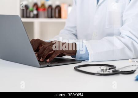 Aufnahme eines nicht erkennbaren männlichen Arztes, der an seinem Laptop arbeitet, während er in seinem Büro sitzt Stockfoto
