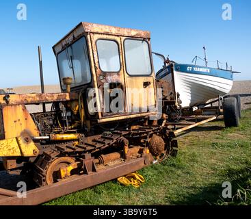 Weybourne, Norfolk, Vereinigtes Königreich – 10. Mai 2025. Rostiger Traktor schleppte früher Fischerboote wie die Anna Gail zum und vom Wasser am Weybourne Beach Stockfoto