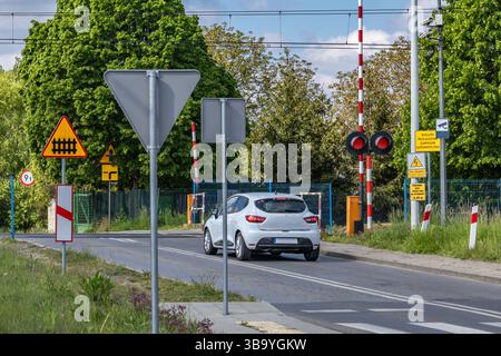 Autos passieren einen Bahnübergang mit roter Ampel, beschädigte Bahnbarrieren am Übergang, Verkehrsverletzung Stockfoto