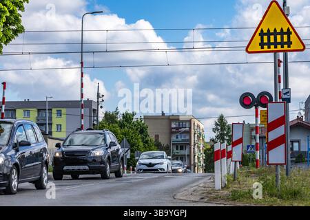 Autos passieren einen Bahnübergang mit roter Ampel, beschädigte Bahnbarrieren am Übergang, Verkehrsverletzung Stockfoto