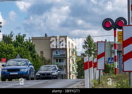 Autos passieren einen Bahnübergang mit roter Ampel, beschädigte Bahnbarrieren am Übergang, Verkehrsverletzung Stockfoto