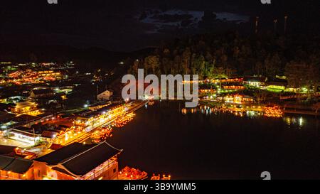 In der Abenddämmerung säumten die Lichter des Dorfes den See in chinesischen Strukturen mit farbenfrohen Lichtern. Ban Rak Thai ist Stockfoto