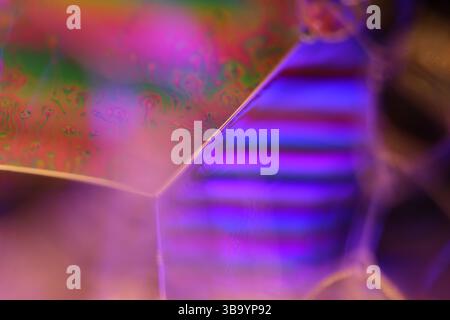 Grüne, orange und lila Flüssigkeitsreflexionen auf dunklem Hintergrund, helle Flüssigkeitsoberfläche Stockfoto