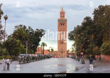 6. März 2025, Marrakesch, Marokko: Pferdekutschen stehen in einer Reihe auf einer nassen Straße bei der berühmten Koutoubia-Moschee, nach Regen Stockfoto