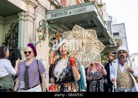 London, Großbritannien. 11. Mai 2025. Elegant gekleidete Personen nehmen am fünften Grand flâneur Walk Teil, vorbei am Kaufhaus Fortnum & Mason. Die Veranstaltung beginnt an der Beau Brummell-Statue in der Jermyn Street und ist definiert als ein Spaziergang ohne Zweck, der die Kunst der flâneur zelebriert, ohne etwas bestimmtes zu tun, und als Gegenmittel für die Anforderungen des modernen Lebens und des digitalen Smartphones. Quelle: Stephen Chung / Alamy Live News Stockfoto