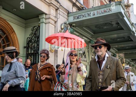 London, Großbritannien. 11. Mai 2025. Elegant gekleidete Personen nehmen am fünften Grand flâneur Walk Teil, vorbei am Kaufhaus Fortnum & Mason. Die Veranstaltung beginnt an der Beau Brummell-Statue in der Jermyn Street und ist definiert als ein Spaziergang ohne Zweck, der die Kunst der flâneur zelebriert, ohne etwas bestimmtes zu tun, und als Gegenmittel für die Anforderungen des modernen Lebens und des digitalen Smartphones. Quelle: Stephen Chung / Alamy Live News Stockfoto