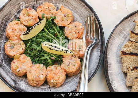 Vorspeise mit Lachs Tartar. Frischer roher Fisch Vorspeise. Es werden Mini-Portionen serviert. Elegantes Gericht mit Meeresfrüchten. Rucola und Garnitur. Leckerer Restaurant-Stil. Stockfoto