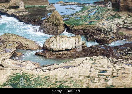 Felsige Küste mit Wasser. Naturstein und Wellen. Gezeitenbecken am Ufer. Meereslandschaft. Wilde Küstenlandschaft. Raues Gelände am Meer. Stockfoto