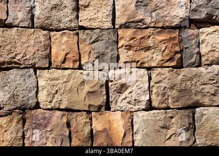Wandstruktur aus Naturstein. Rustikales Muster von Felsen. Braune und beige Steinoberfläche. Alte Mauerwerkkonstruktion. Raues Baumaterial. Stockfoto